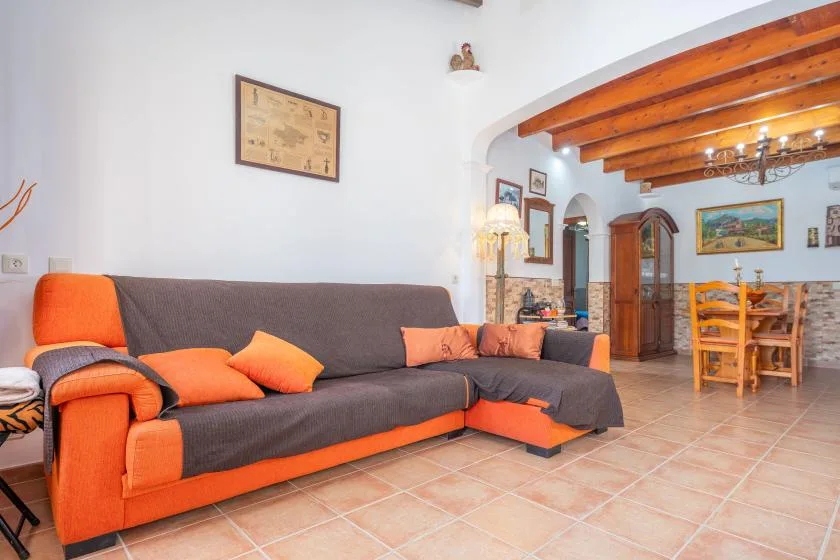 Sala de estar con un sofá naranja y gris y una mesa de comedor de madera.