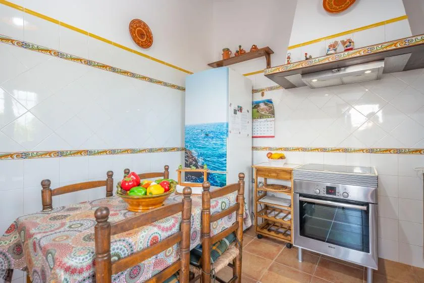 Una cocina y comedor con azulejos y una mesa junto al horno.