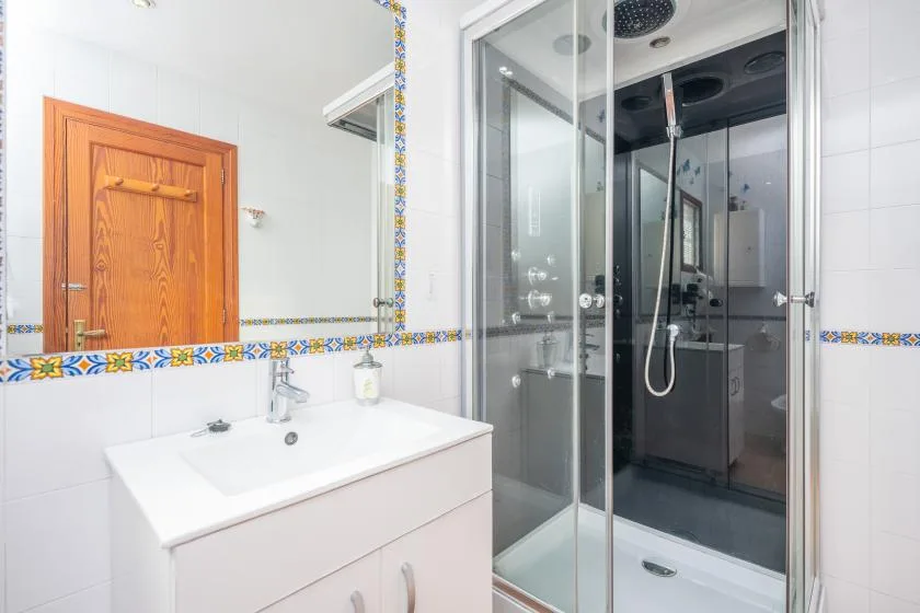 Un baño con un lavabo bajo un espejo grande y una ducha de cristal.