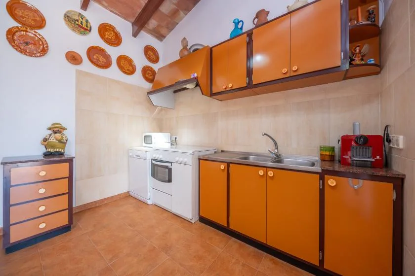 Una cocina con armarios naranjas, una estufa y un fregadero.
