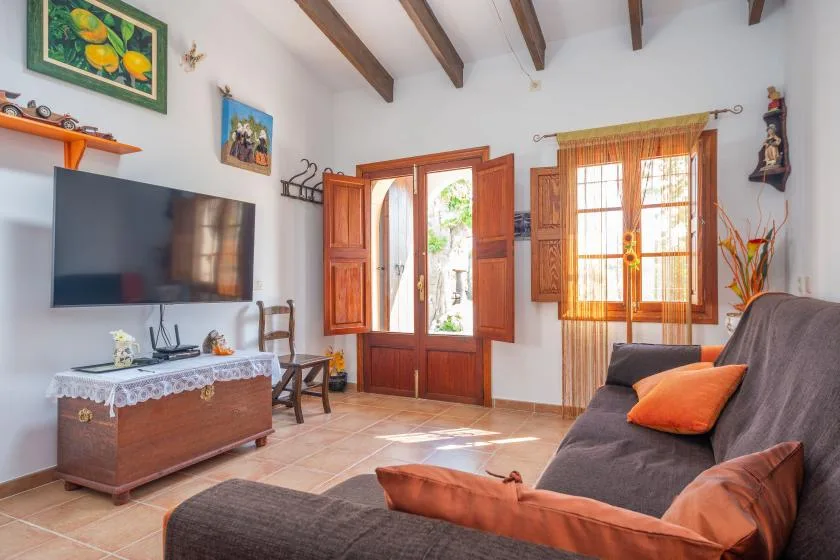 Una sala de estar luminosa con vigas de madera a la vista y ventanas.