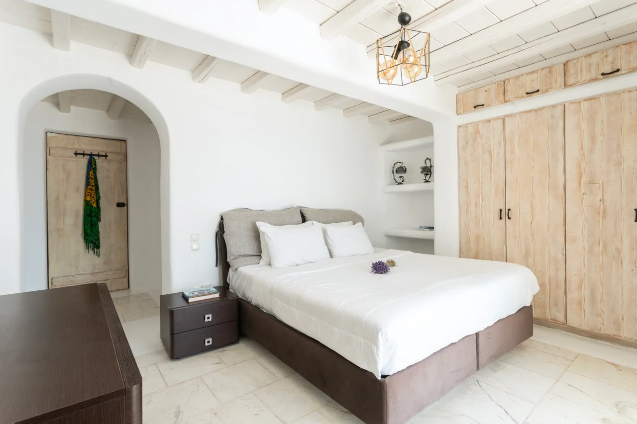 A bright bedroom with a neatly made bed and light wood cabinetry.
