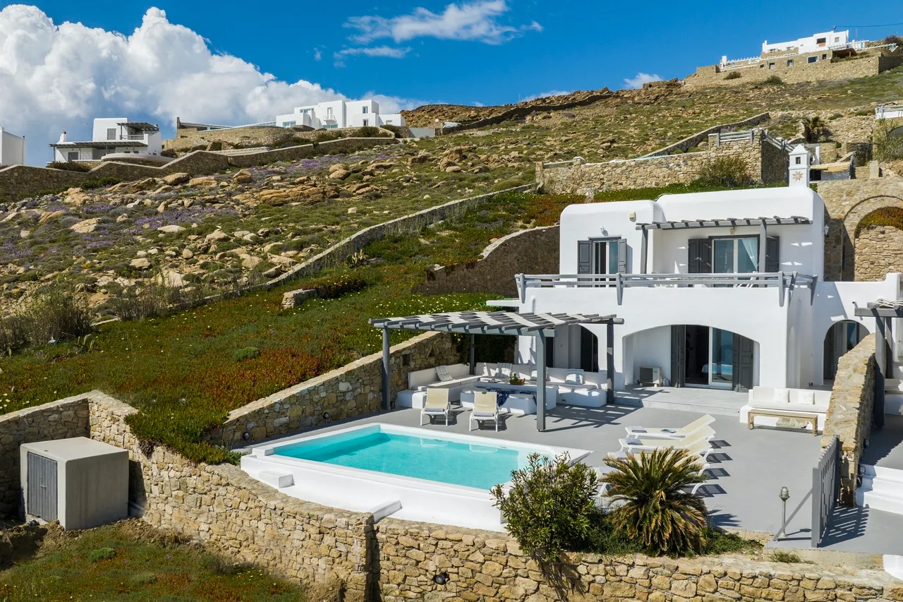 A hillside villa with a swimming pool and outdoor seating.