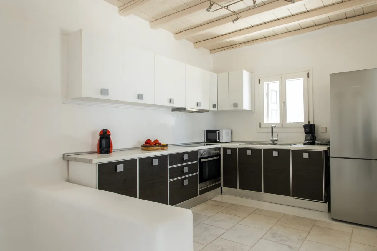 A bright kitchen with dark lower cabinets and a stainless steel refrigerator.