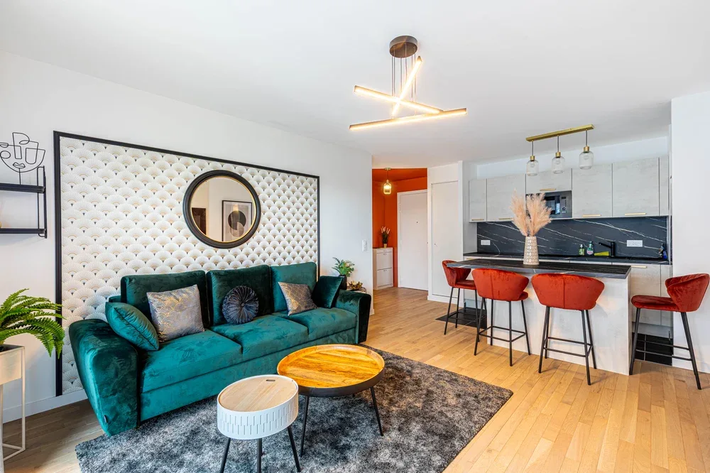 Una sala y cocina de concepto abierto cuenta con asientos color turquesa y una isla.