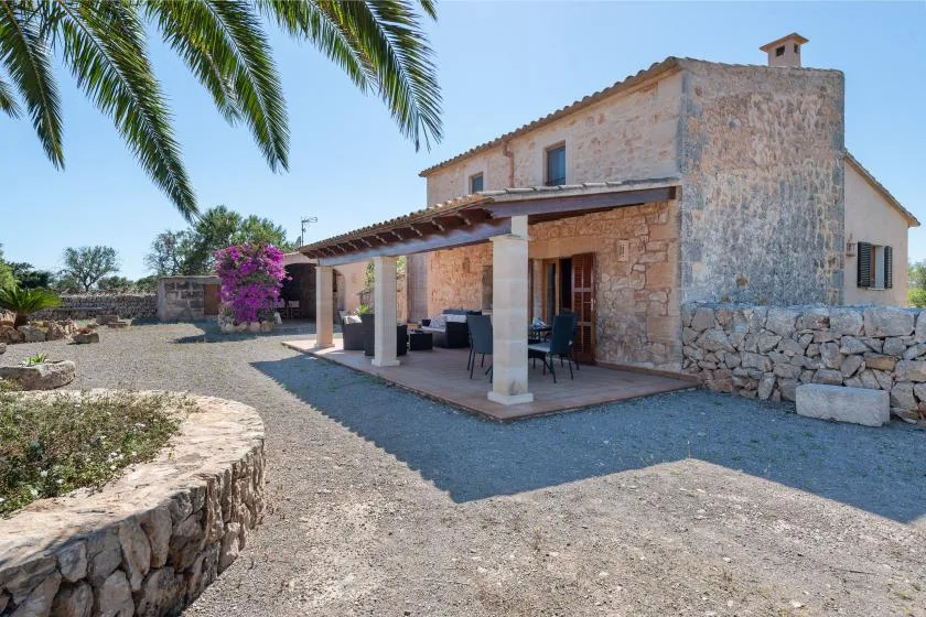 Casa de piedra con patio cubierto y patio de grava.