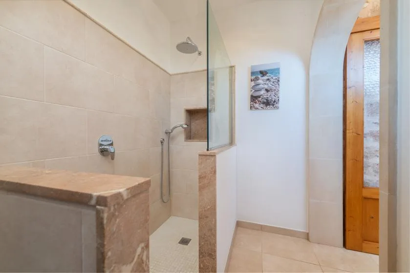 Un baño alicatado con una zona de ducha y una puerta de madera.