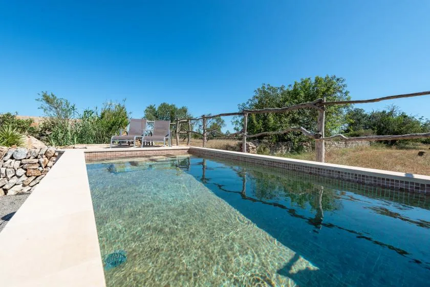 Una piscina al aire libre con agua clara y asientos al lado.