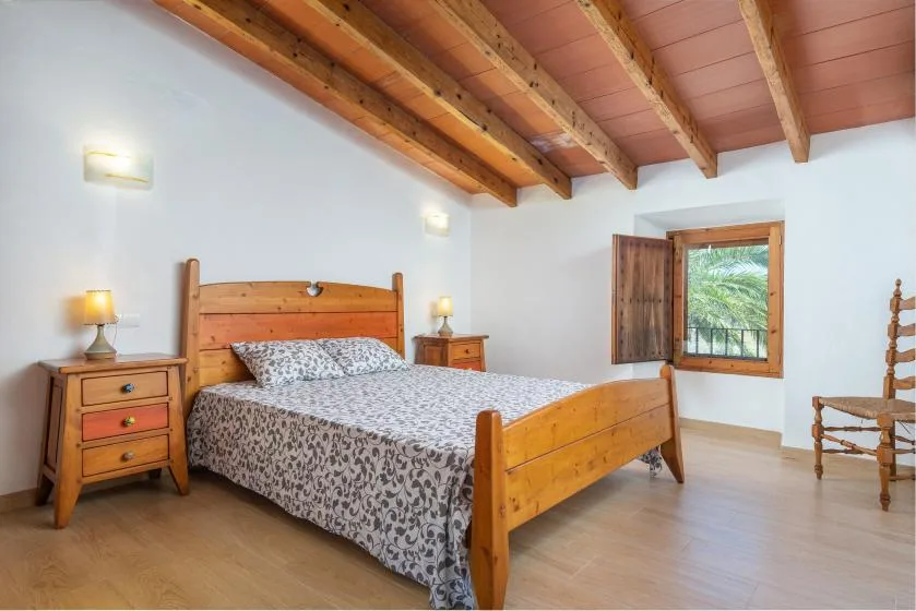 Un dormitorio con cama de madera, mesitas de noche a juego y una ventana.