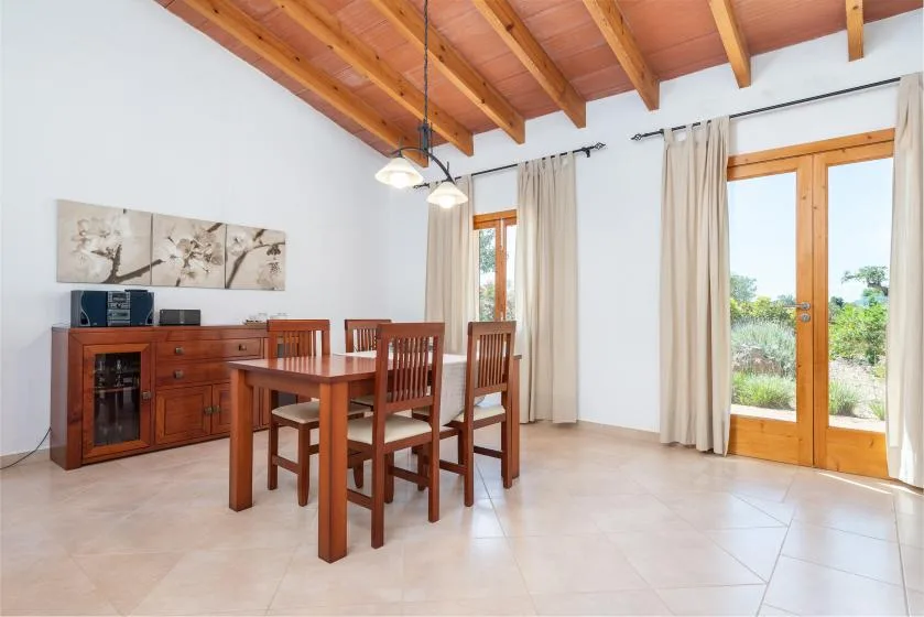 Un comedor con una mesa y sillas de madera junto a puertas de vidrio.