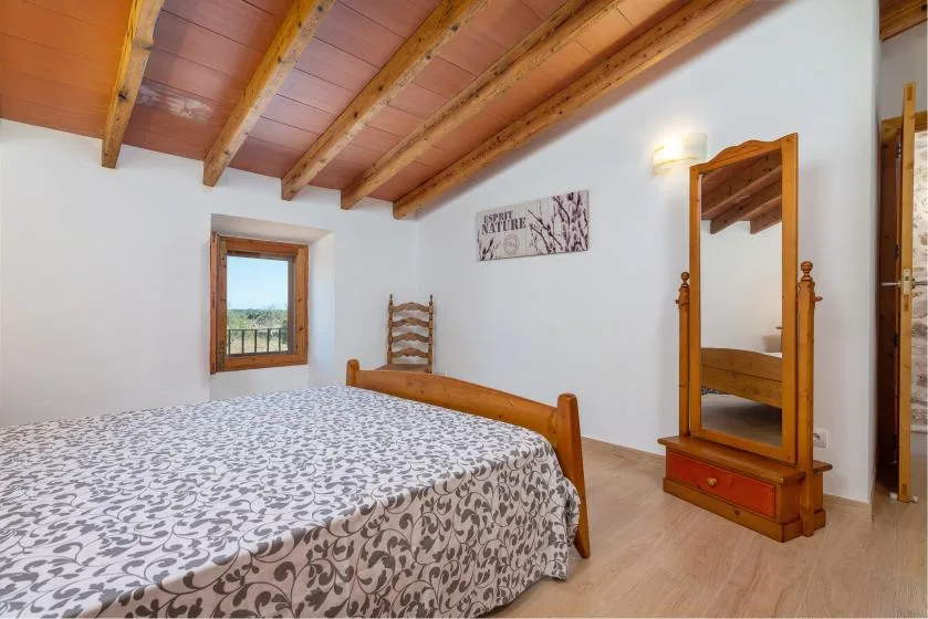 Un dormitorio con una colcha estampada y un espejo con marco de madera.