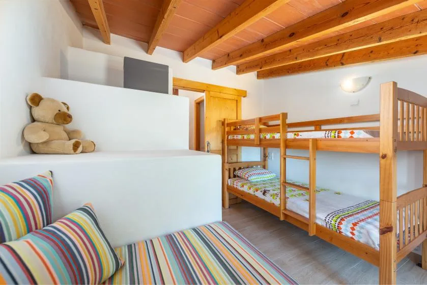 Un dormitorio con literas de madera y ropa de cama a rayas de colores.