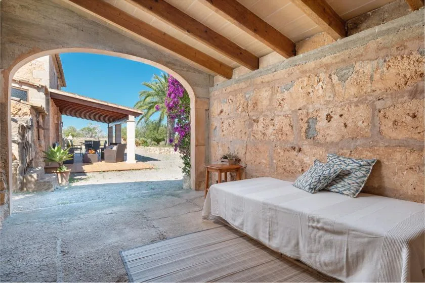 Un dormitorio con paredes de piedra se abre a un patio exterior a través de un arco.