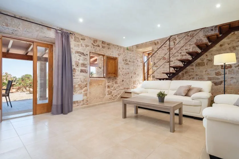 Una sala luminosa con paredes de piedra, asientos y una escalera.