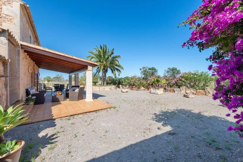 Un patio cubierto con asientos al aire libre da a un jardín de grava.