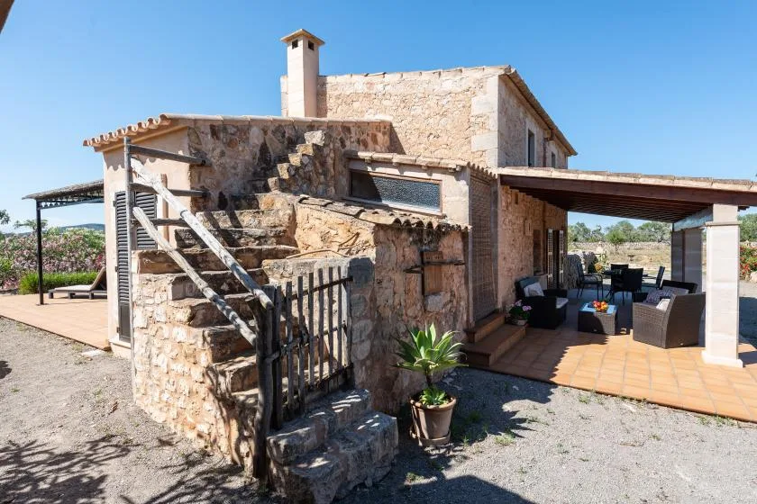 Una casa de piedra con una escalera exterior y un patio cubierto.
