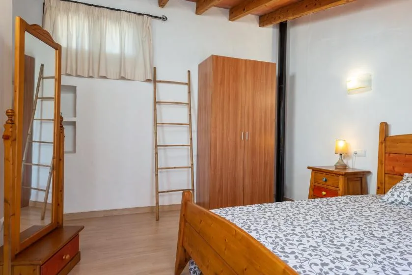 Un dormitorio con cama de madera, armario y mesita de noche.