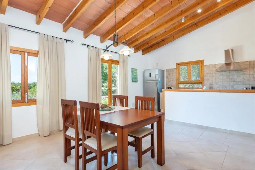 Comedor con una mesa de madera y asientos junto a una cocina abierta.