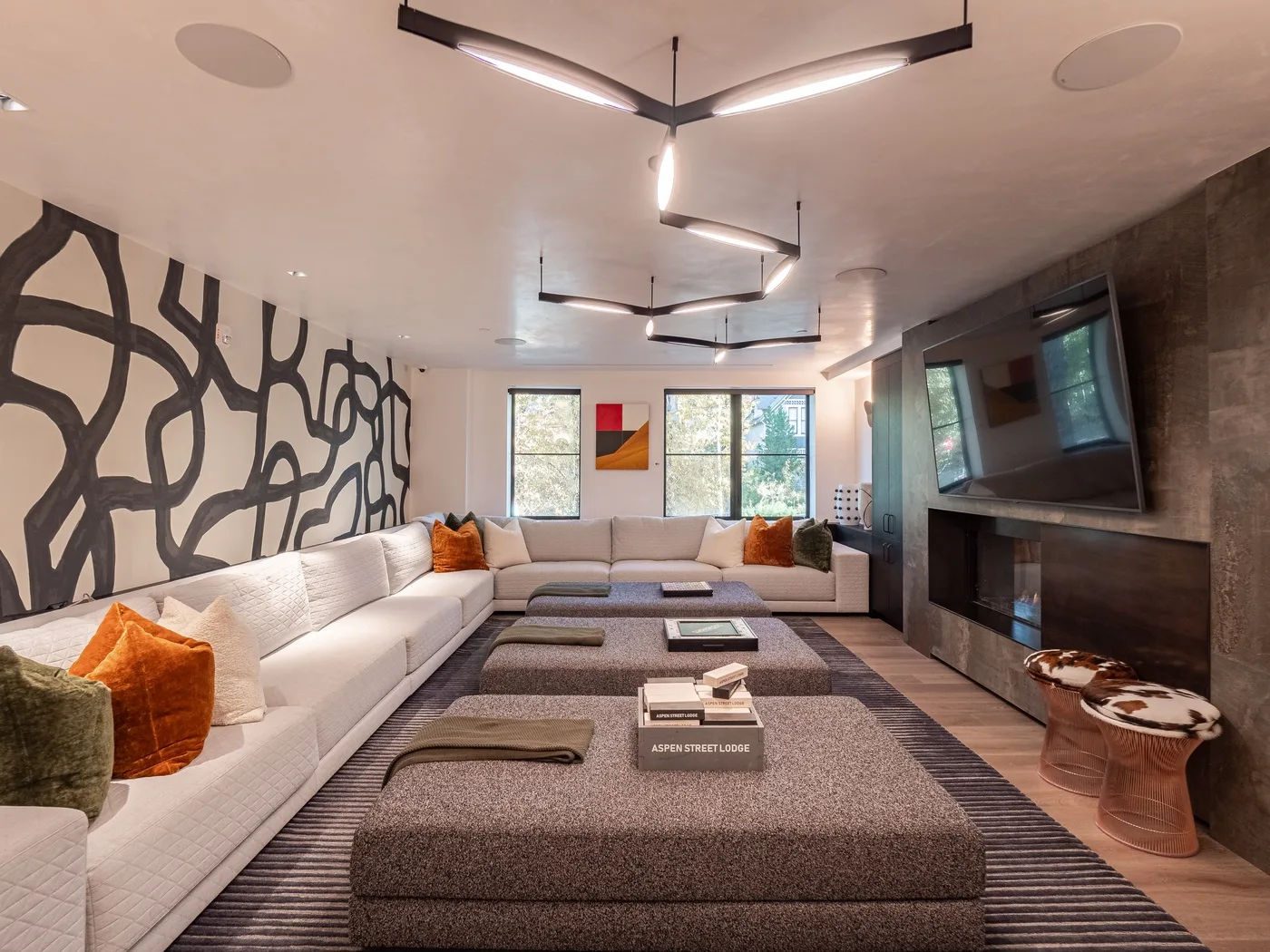 A modern lounge with sectional seating, a low table, and a wall-mounted television.