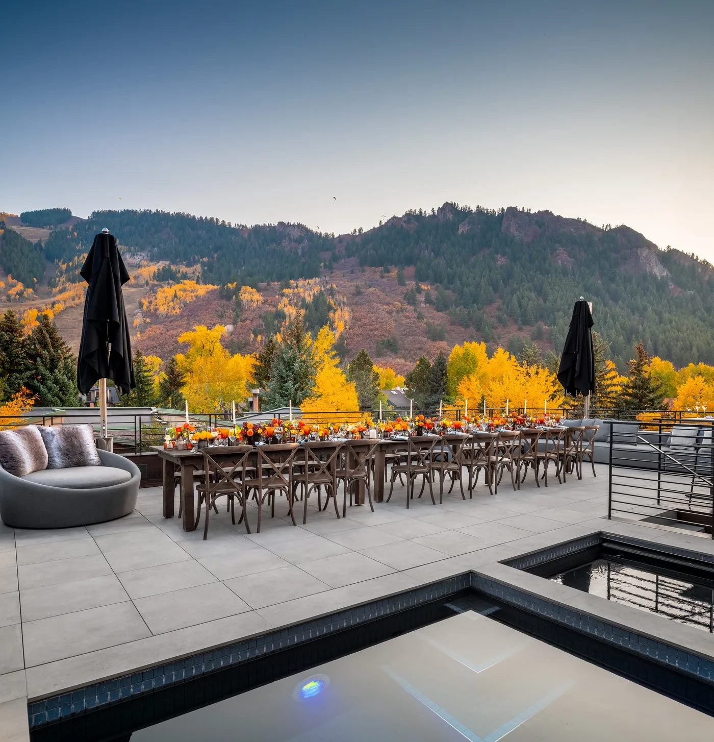 A terrace dining area overlooks autumn-colored trees and a mountain ridge.