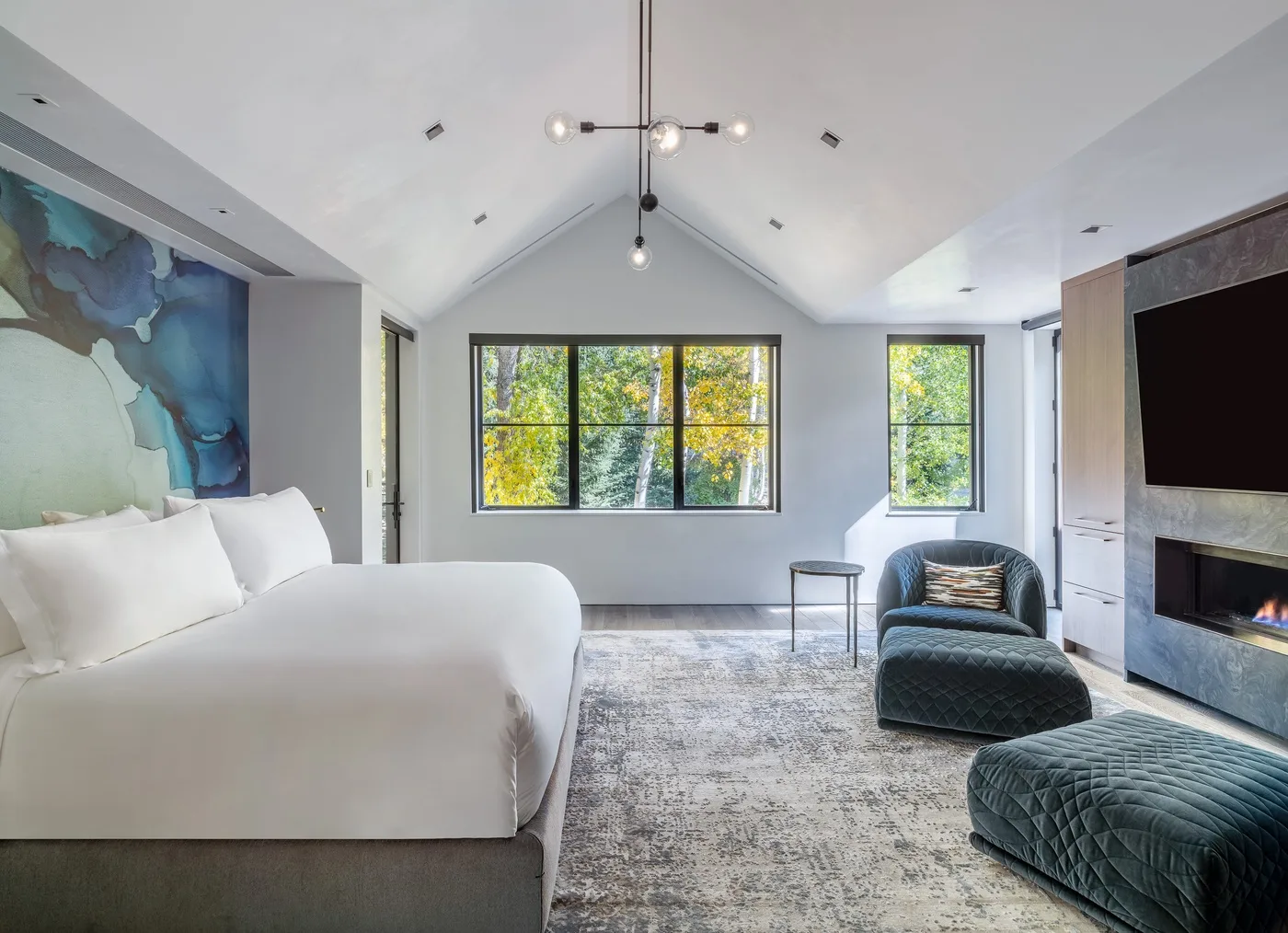 A bright bedroom with a large bed, windows, and a seating area.