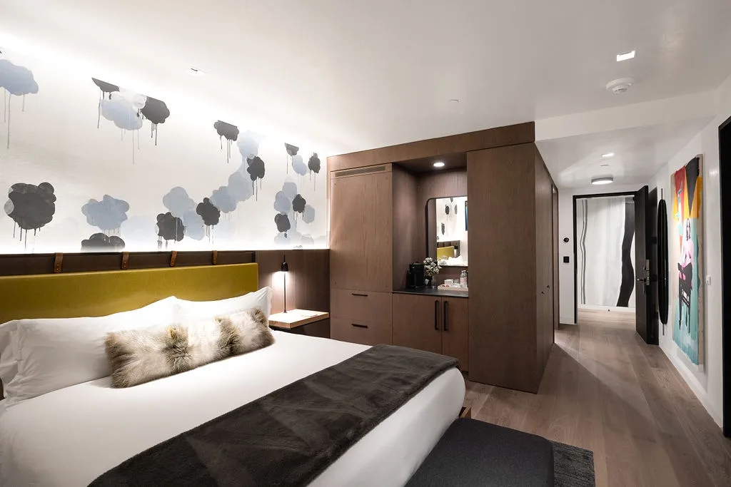 A bedroom with a bed, patterned wall, and built-in cabinetry.