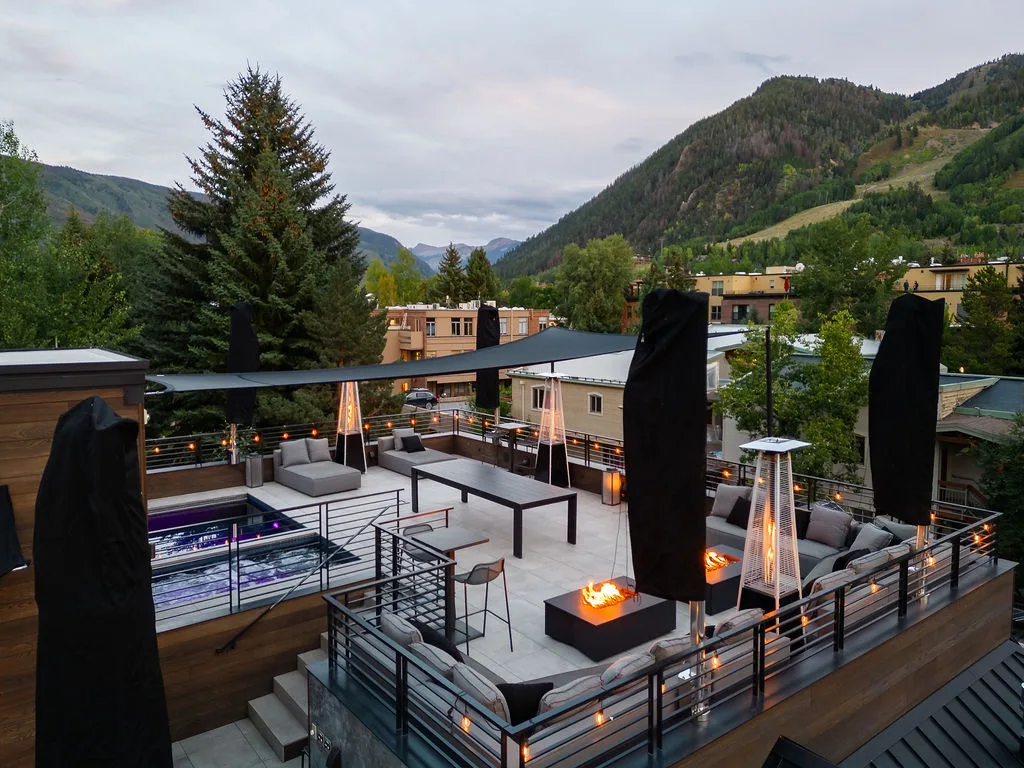 A rooftop patio with seating, a hot tub, and mountain views.