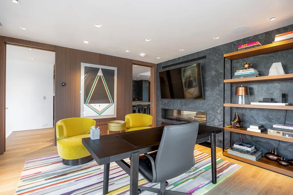 A living room with a television, seating, and a dining table on a striped rug.