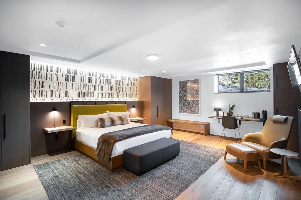 A modern bedroom with a bed, desk, and seating area.