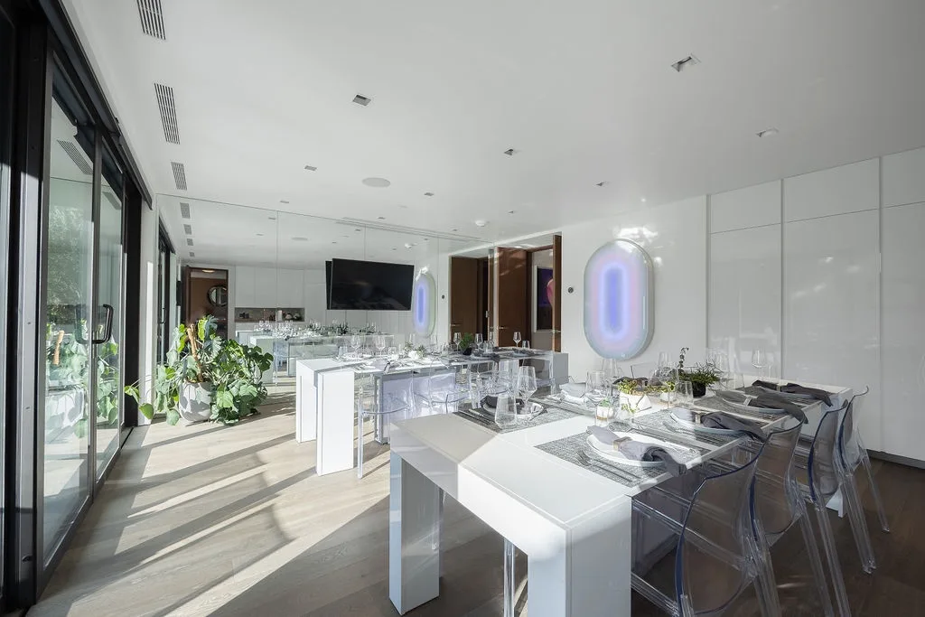 A bright modern dining area with a long table and transparent seating.