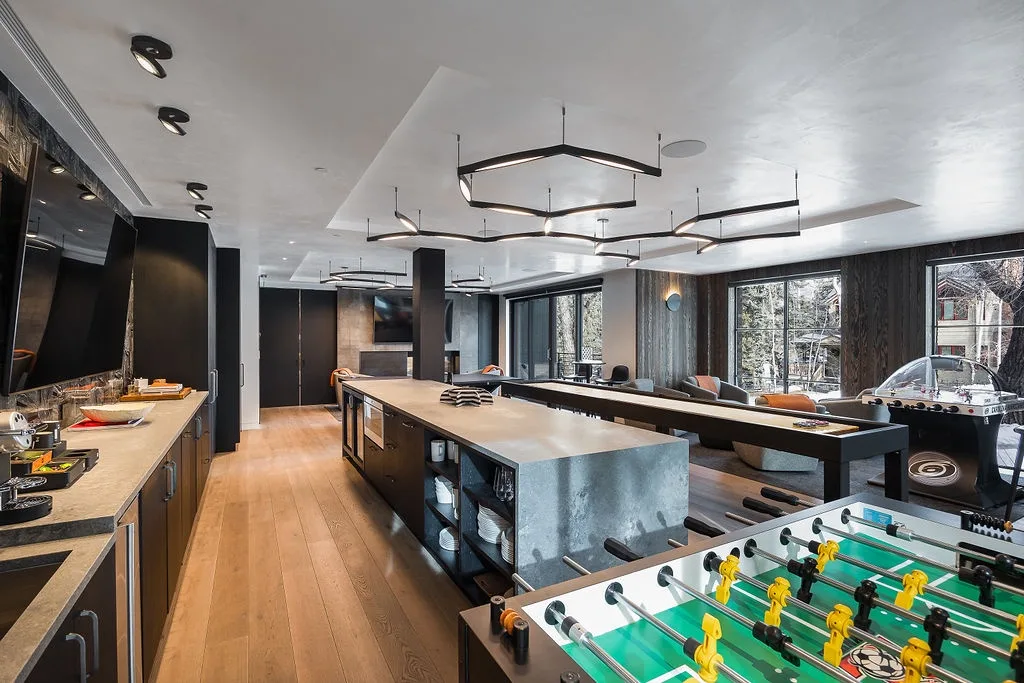 A modern recreation room features a long counter and a foosball table.