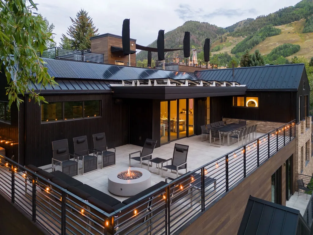 A mountain lodge deck with outdoor seating and a built-in fire feature.