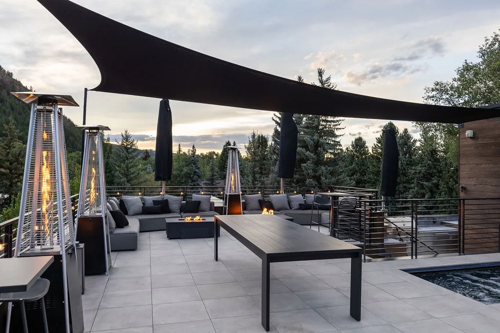 An outdoor patio with lounge seating, a long table, and a shade canopy.