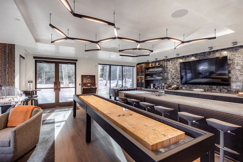 A modern bar and lounge features a long wooden counter and seating.