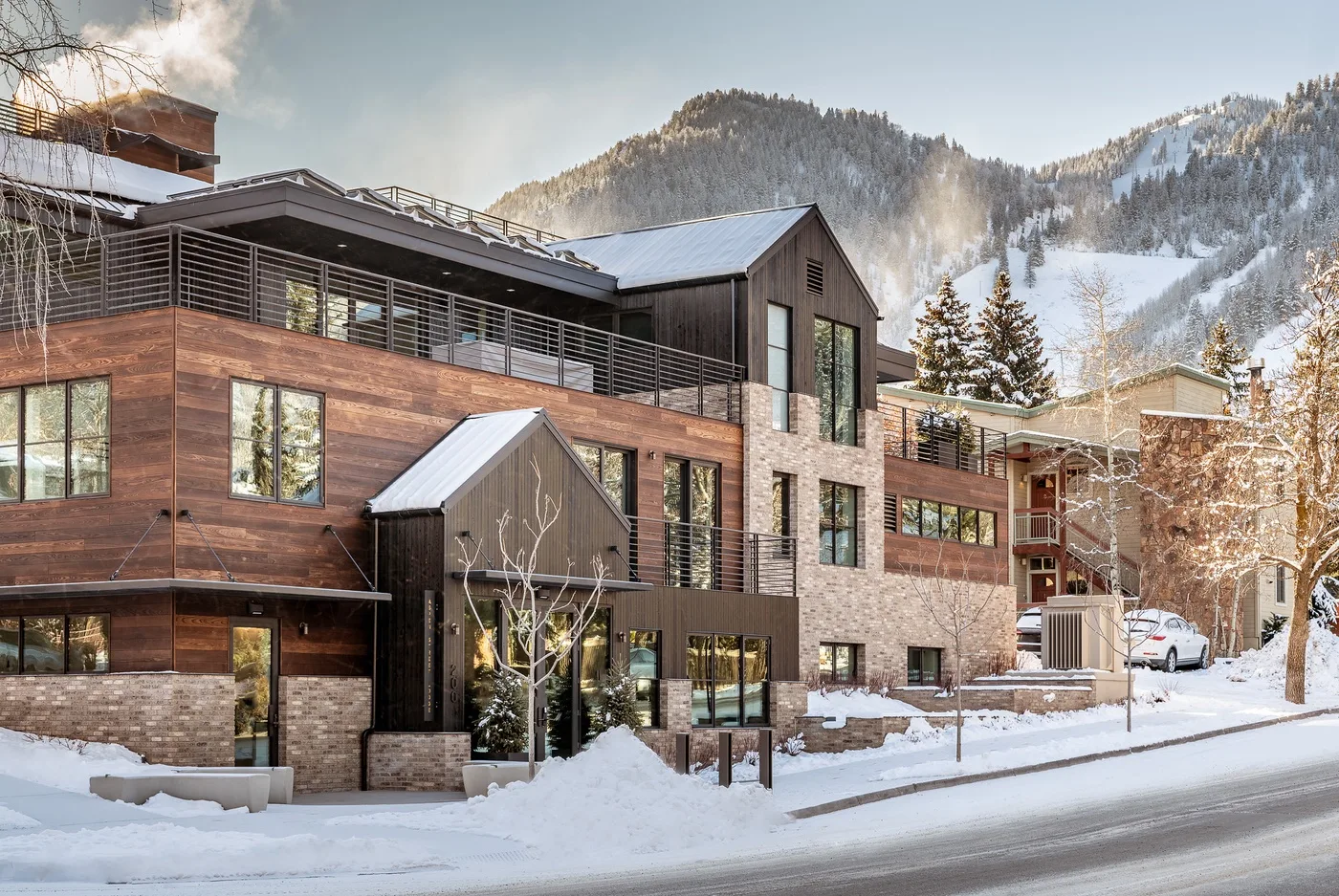 A modern multi-story building stands beside a snowy mountain road.