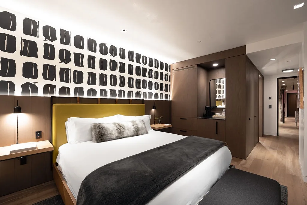 A bedroom with a neatly made bed and bold black-and-white wall art.