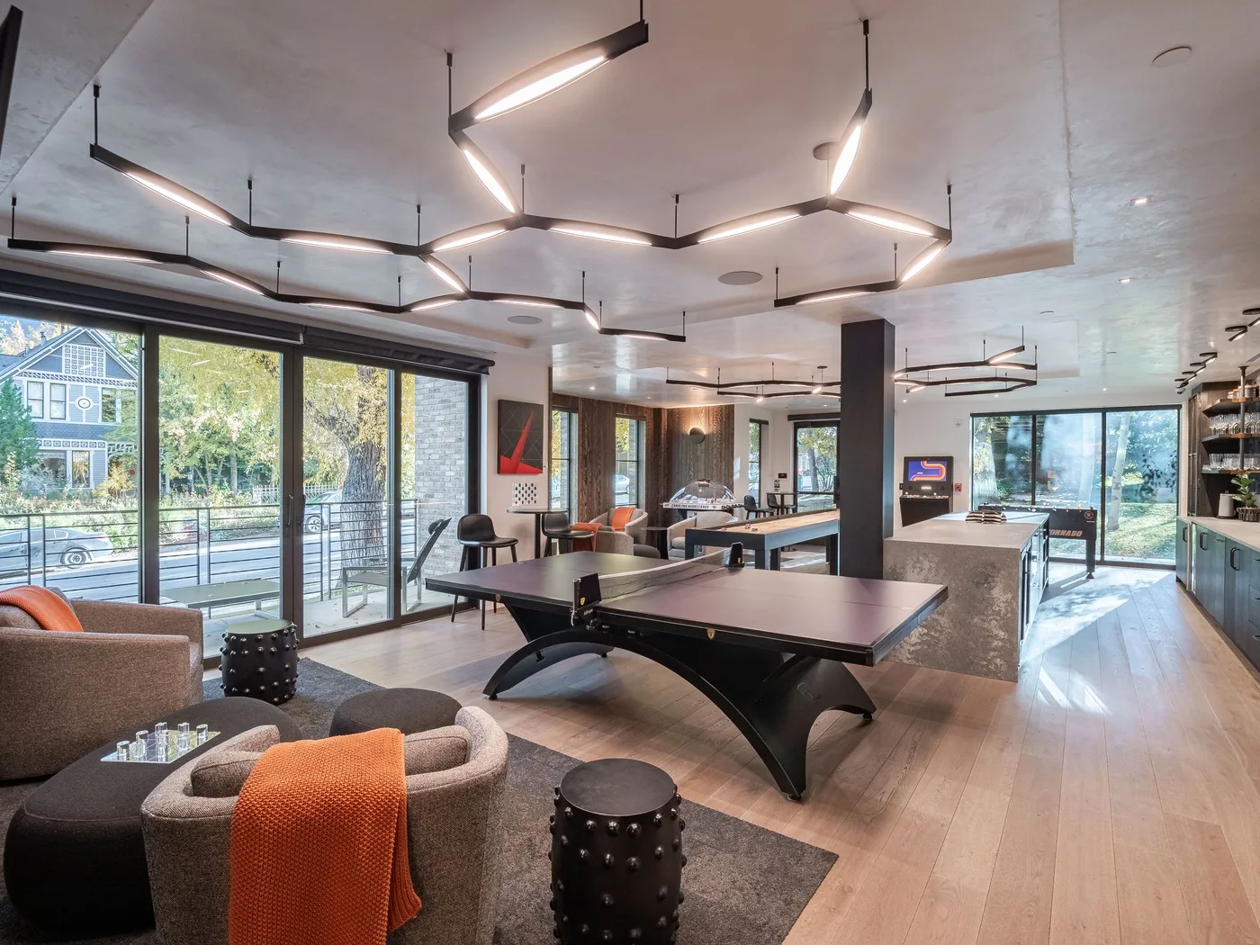 A modern lounge with seating, tables, and large windows overlooking greenery.