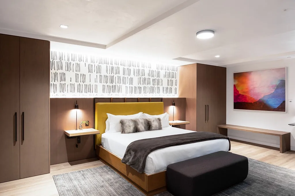 A bedroom with a bed, bedside tables, and a colorful abstract painting.