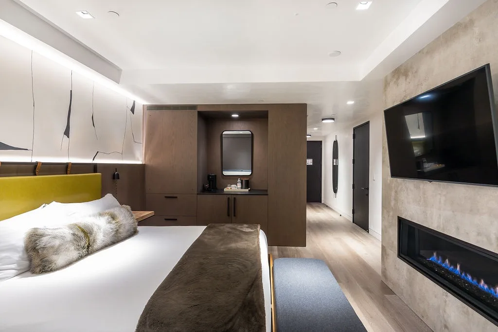 A modern bedroom with a bed, a wall-mounted television, and a fireplace.
