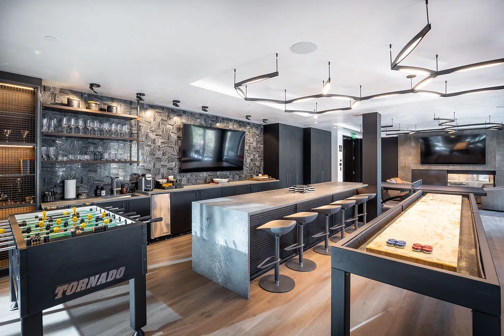 A game room features a foosball table, a long counter, and tabletop shuffleboard.