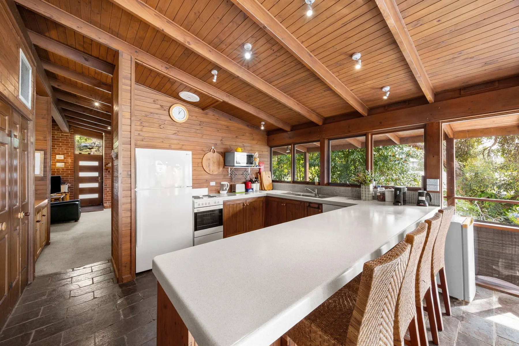 A spacious kitchen with a long island and windows overlooking greenery.