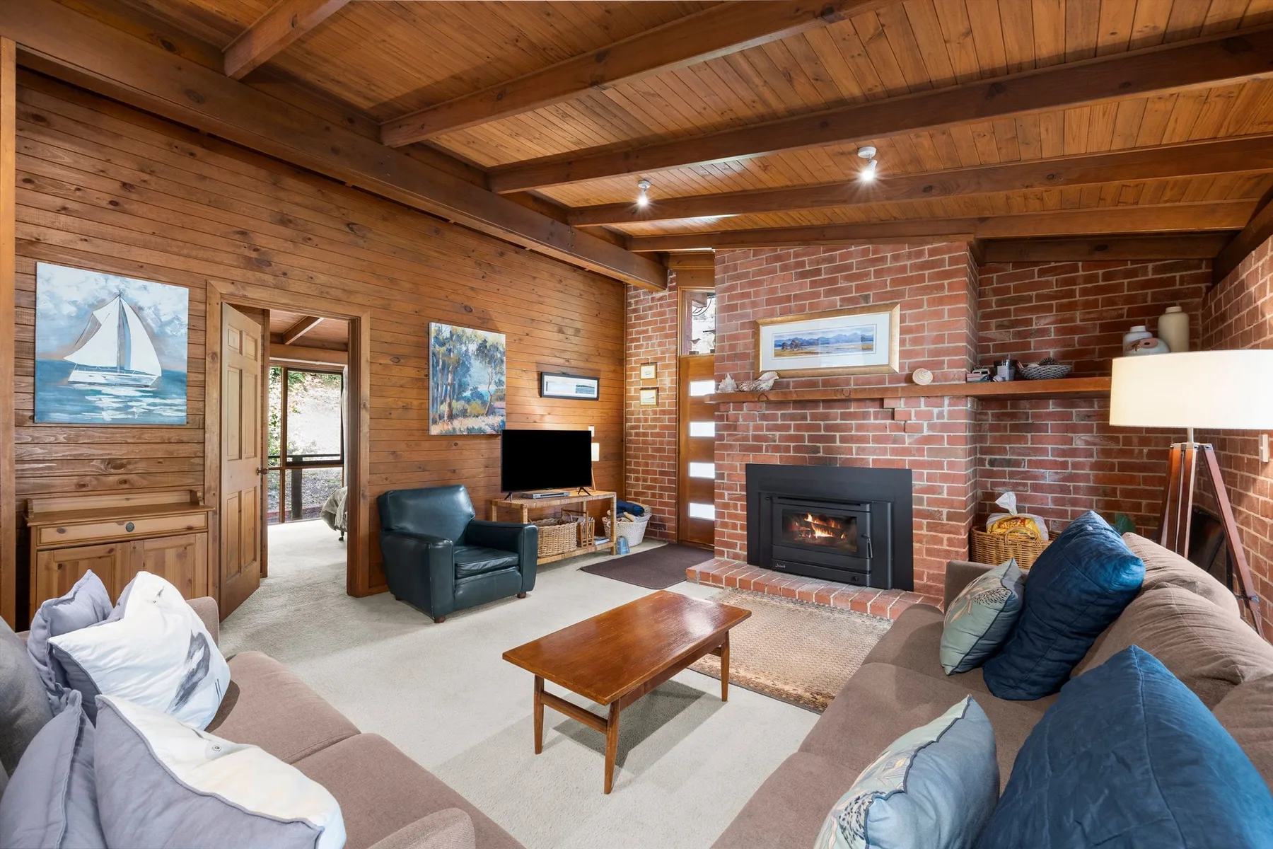 A living room with seating arranged around a brick fireplace and television.