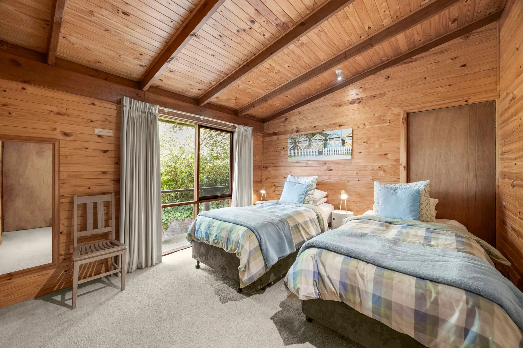 A wood-paneled bedroom with two beds and a large window.