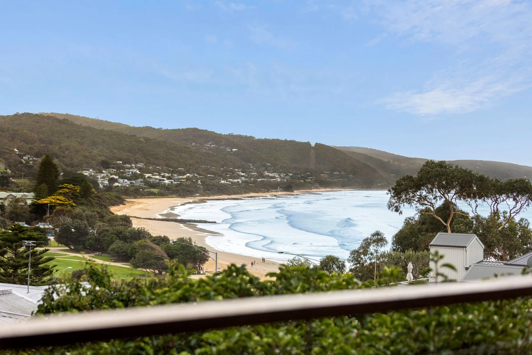 Coastal bay with a sandy beach, rolling hills, and ocean waves.