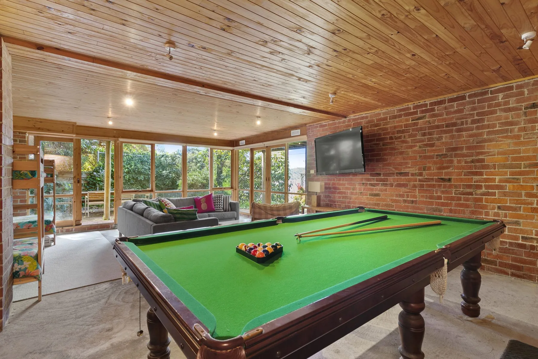 A game room with a pool table, seating, and large windows.