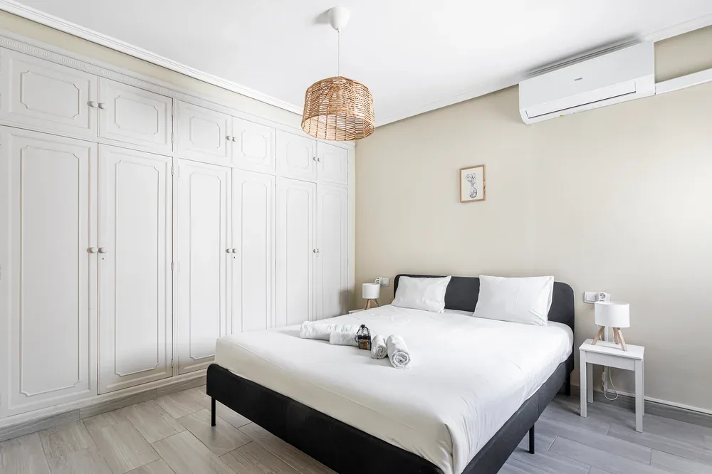 A bright bedroom with a neatly made bed and built-in cabinets.
