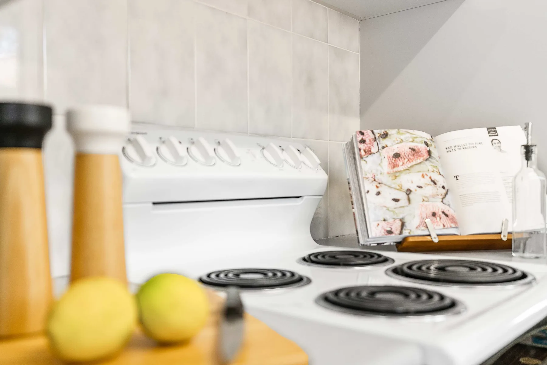 A kitchen stovetop with a cookbook open on the counter.