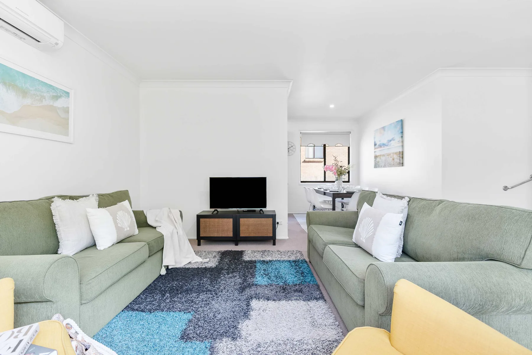 A bright living room with green seating arranged around a television.