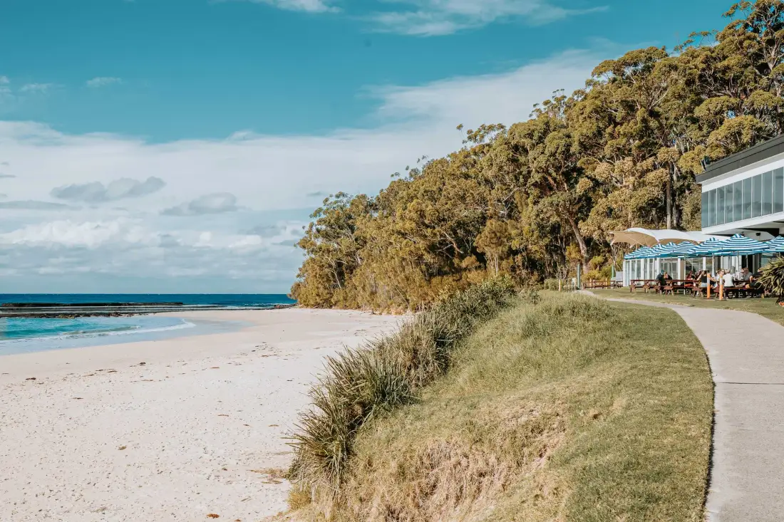 A sandy beach and coastal path beside a seaside building.