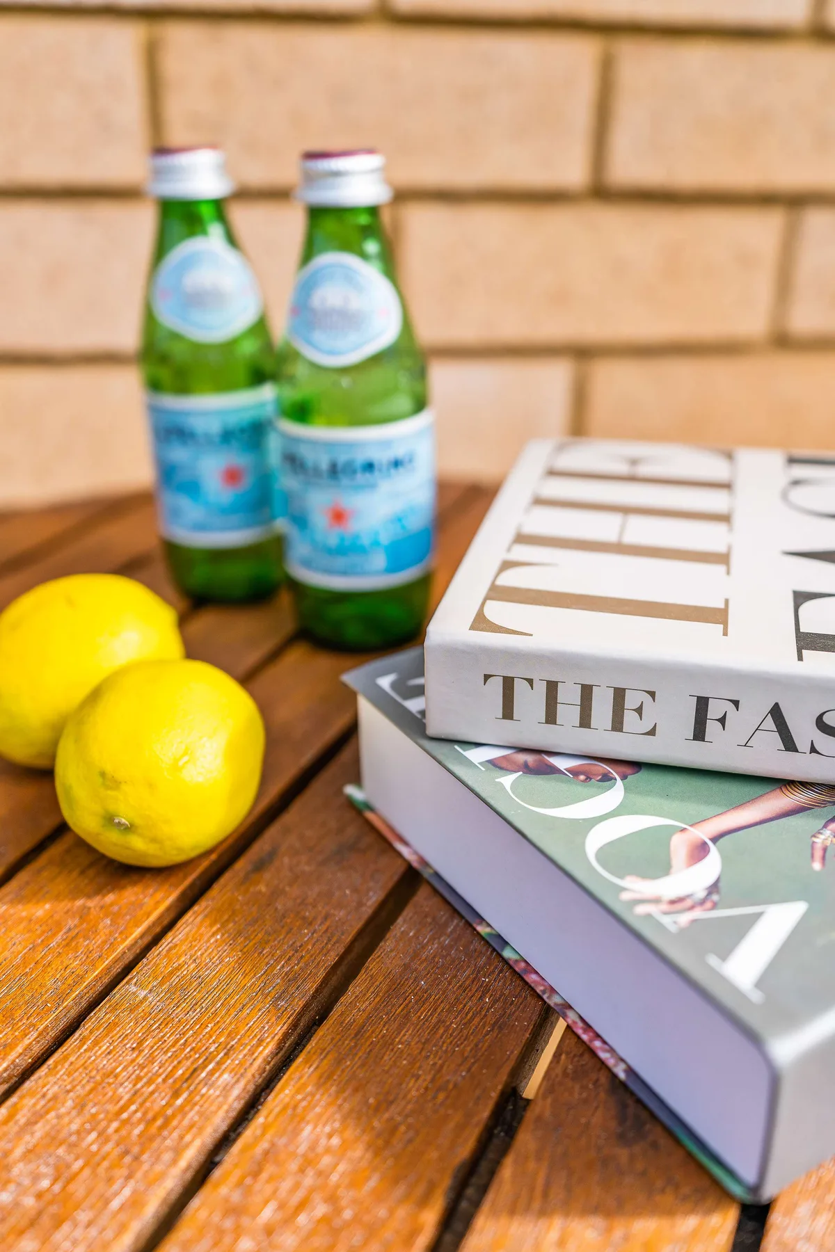 Books, lemons, and bottled drinks sit on a wooden table.